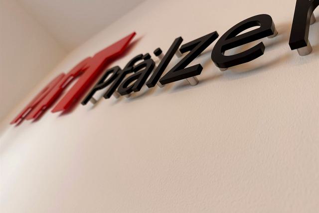 Schräg fotografierter Schriftzug pfälzer mit rotem Logo an einer hellen Innenwand.