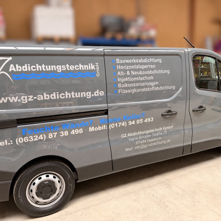Grauer Firmenwagen von GZ Abdichtungstechnik mit großflächiger Werbebeschriftung in einer Halle.