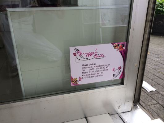 Visitenkarte eines Nagelstudios an einer Glastür neben einem Gehweg