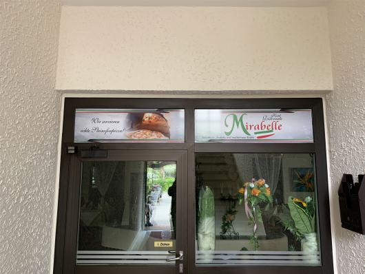 Eingangstür des Hotel Restaurants Mirabelle mit Glasfront und Werbeschildern