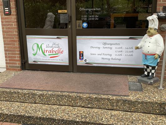 Eingang des Hotels Ristorante Mirabelle mit Öffnungszeiten und Kochfigur vor der Tür.