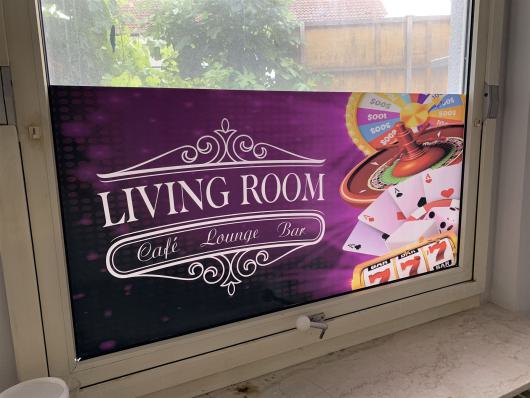 Fenster mit violettem Werbeaufkleber für Living Room Café Lounge Bar und Casino-Motiven
