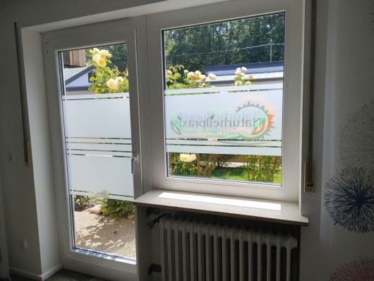 Helles Fenster mit Glastür, Milchglasstreifen und Blick auf blühende Rosen im Garten.