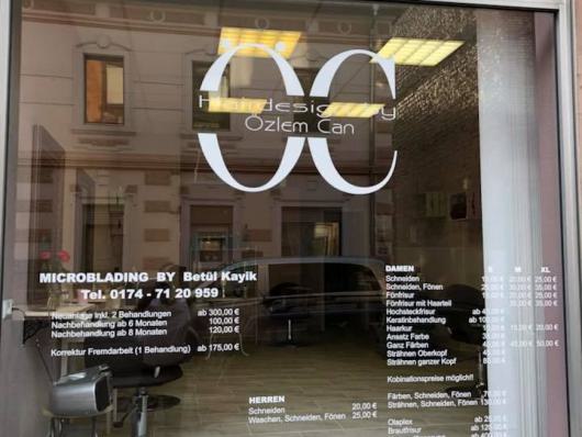 Schaufenster eines Friseursalons mit Preislisten und Spiegelungen der Straße
