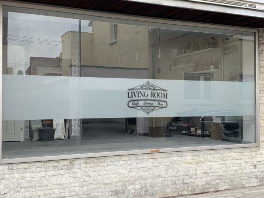 Große Schaufensterfront eines Lokals mit dem Schriftzug LIVING ROOM Café Lounge Bar.