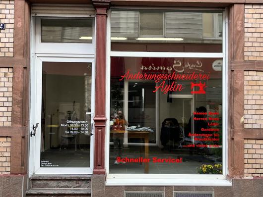 Schaufenster und Eingang einer Änderungsschneiderei mit roter Beschriftung