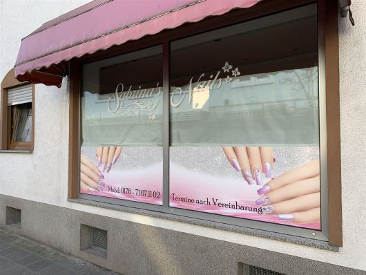 Schaufenster eines Nagelstudios mit rosa Markise und Bildern lackierter Fingernägel