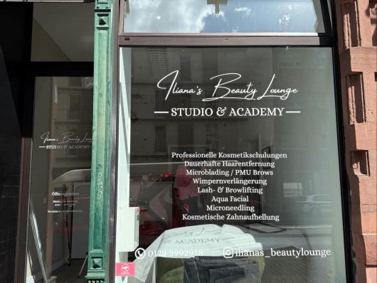 Schaufenster eines Kosmetikstudios mit Beschriftung und Behandlungsraum im Inneren.