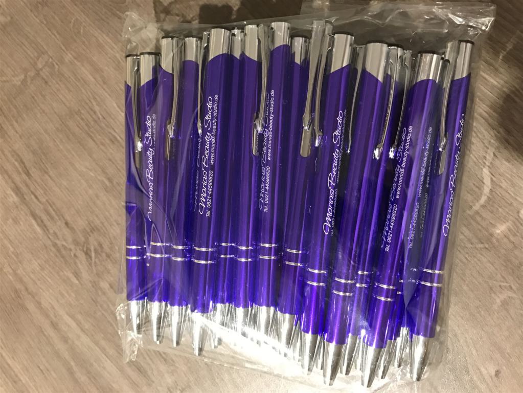 Ein Beutel mit mehreren violetten Kugelschreibern auf einem Holzboden.