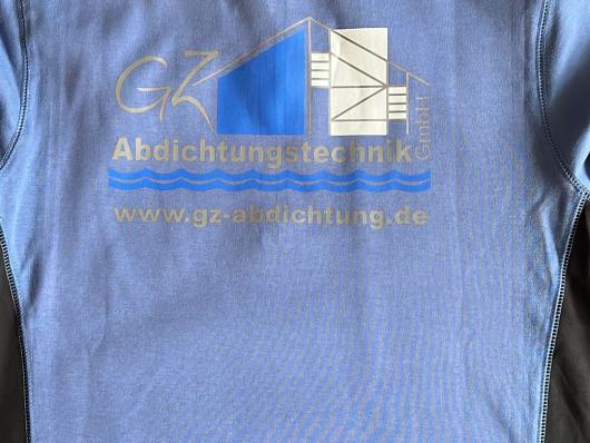 Blaues T-Shirt mit aufgedrucktem Logo und Schriftzug auf einem Teppich