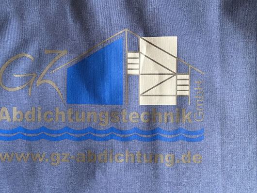 Nahaufnahme eines blauen Shirts mit dem aufgedruckten Logo von GZ Abdichtungstechnik Haag