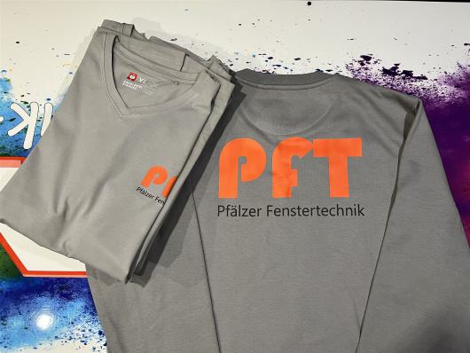 Zwei graue T-Shirts mit orange-schwarzem PFT-Logo liegen übereinander.