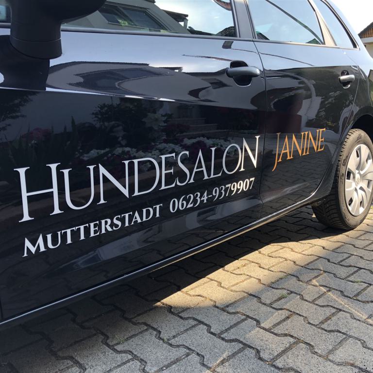 Seitenansicht eines schwarzen Autos mit der Aufschrift Hundesalon Janine und einer Telefonnummer.